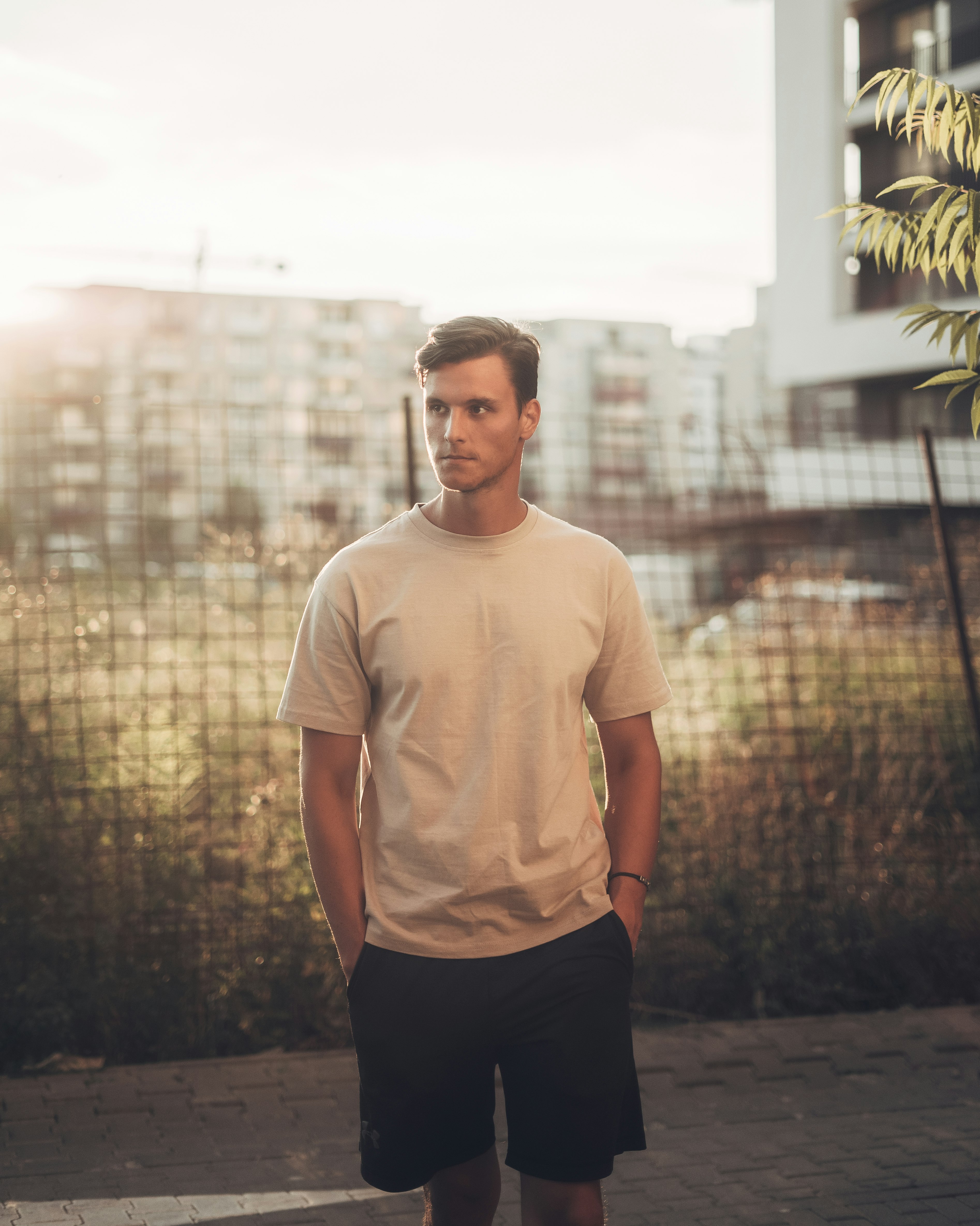 man in white crew neck t-shirt standing near green palm tree during daytime